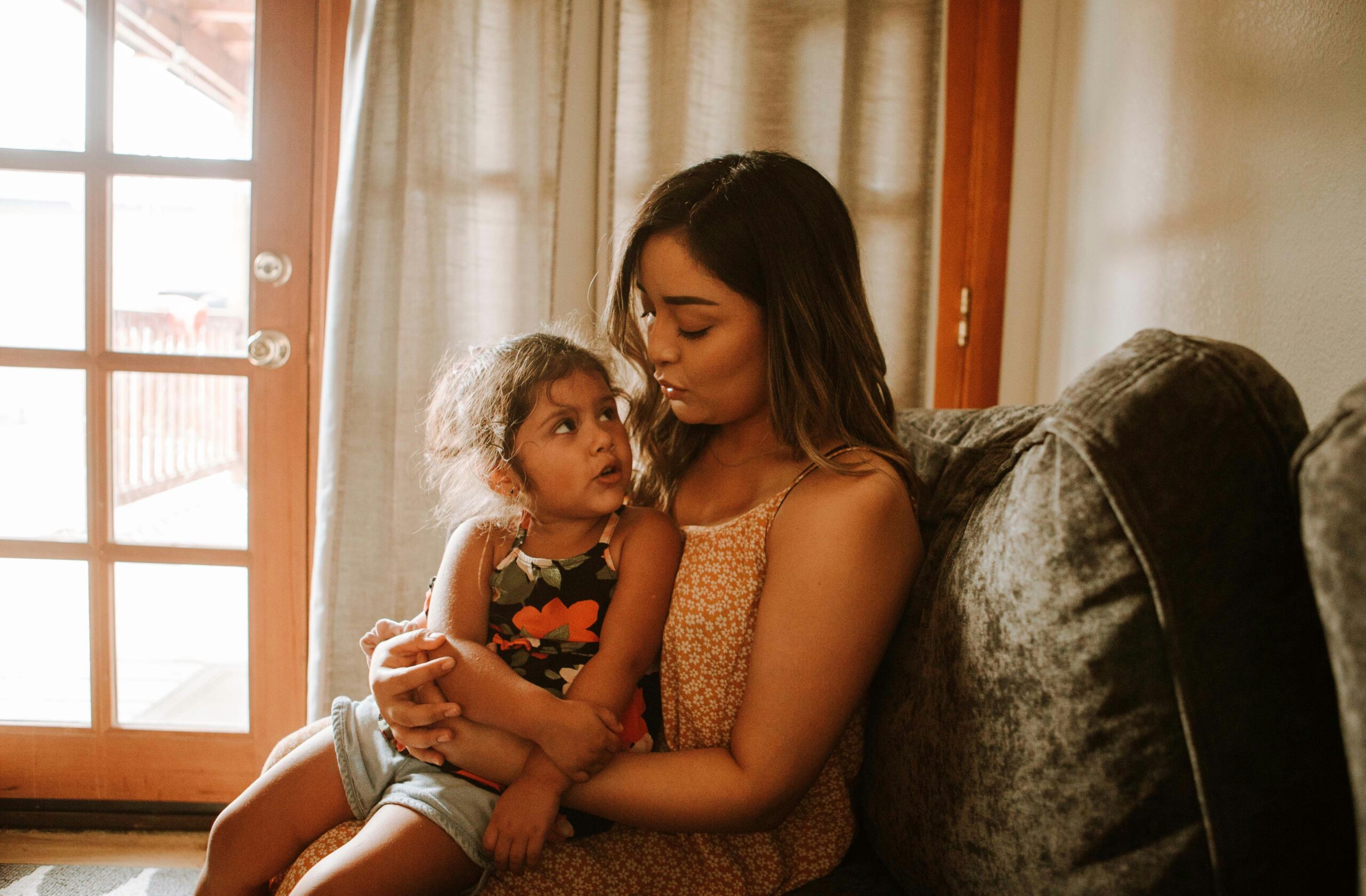 Parent sitting on a couch holding a young child and listening attentively in a calm home setting